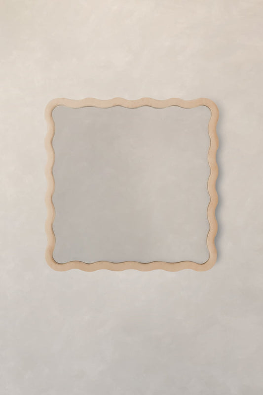 The Onde Mirror Small features a rectangular shape and a wavy light wooden frame, ideal for modern interiors when hung on a pale, textured wall.