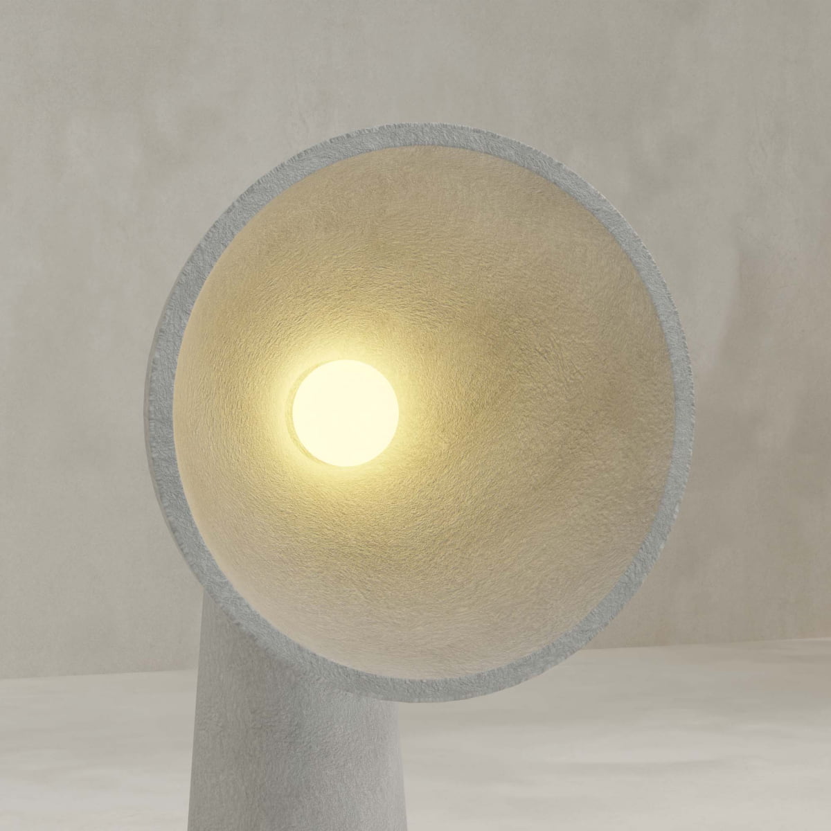 The Orbis Medium Floor Lamp features a circular, cone-shaped design with a textured surface, offering sculptural artistry and casting a warm, soft light from its center against a neutral, minimal background.