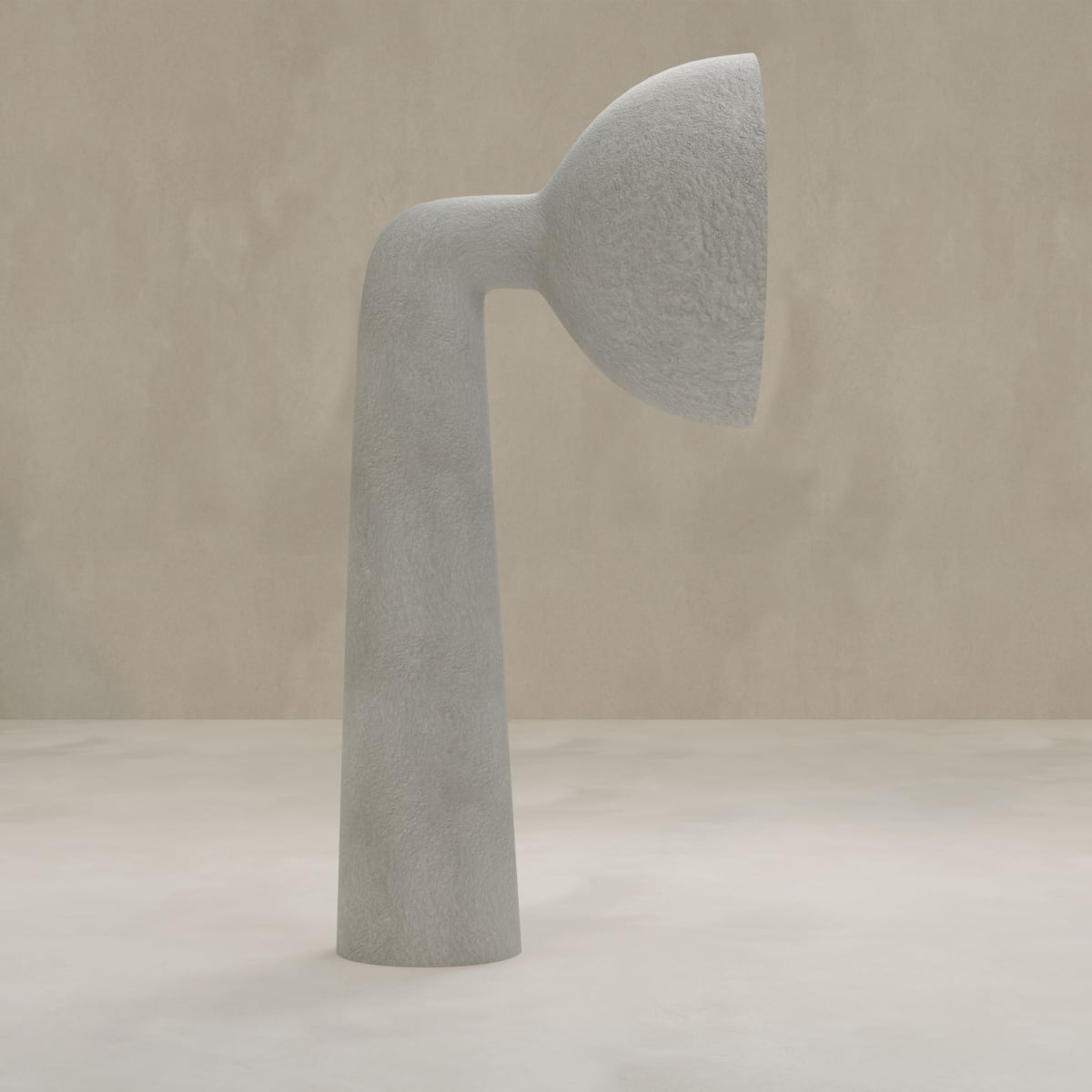 The Orbis Tall Floor Lamp, a minimalist modern piece in light grey natural stone with a bent cylindrical shape and rounded top, stands on a neutral surface against a beige background, highlighting its sculptural artistry.