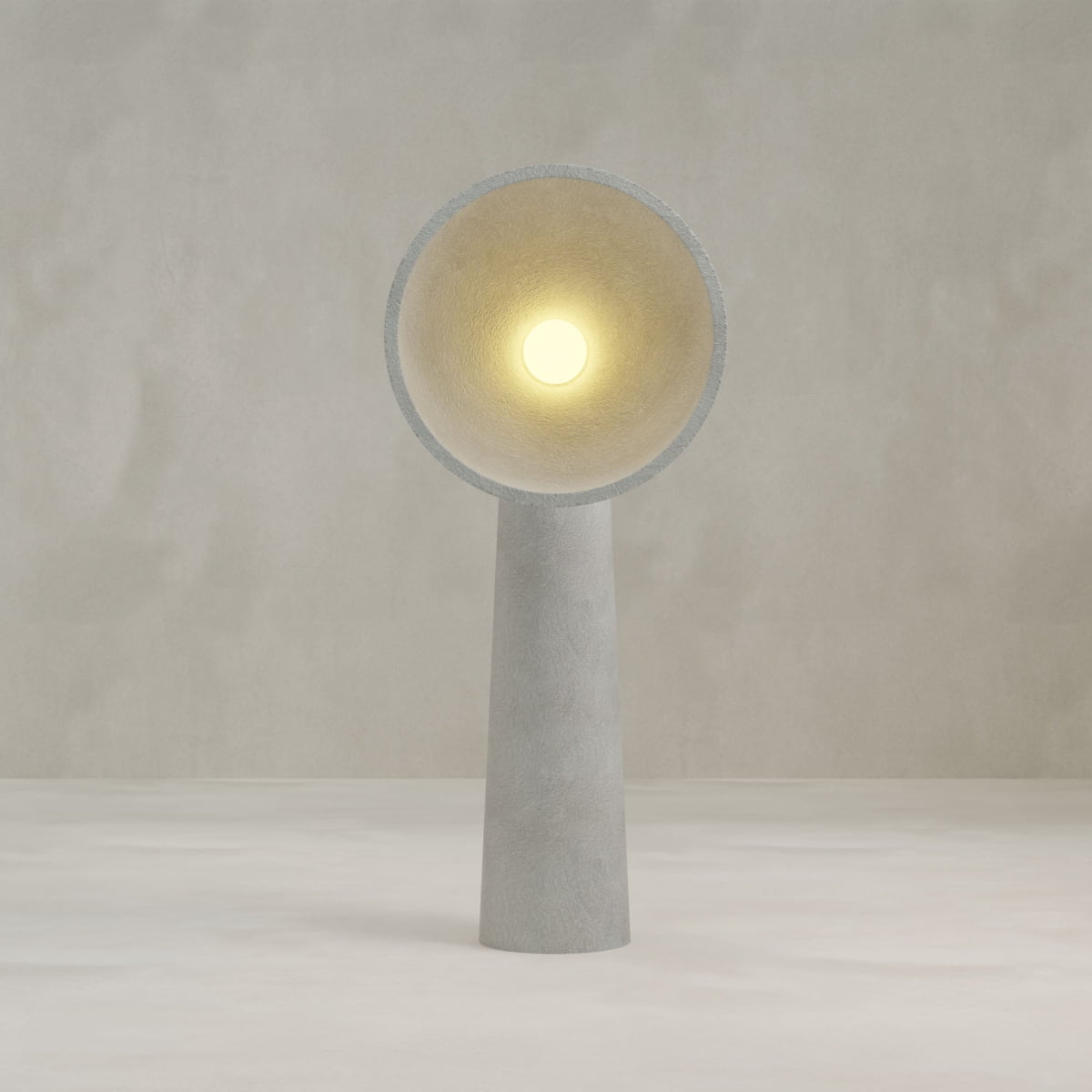 The Orbis Tall Floor Lamp features a modern, minimalist design with a conical base and wide circular shade, casting warm light and embodying sculptural artistry against a neutral, textured backdrop.