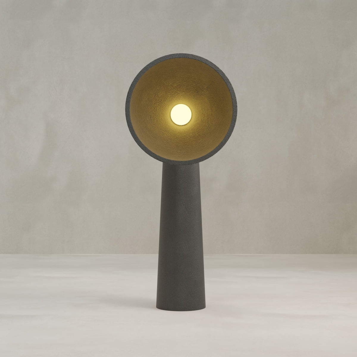 The Orbis Tall Floor Lamp features a modern, dark cylindrical base inspired by sculptural design and a wide circular shade with a golden interior, illuminating a single round bulb against a neutral, textured background.