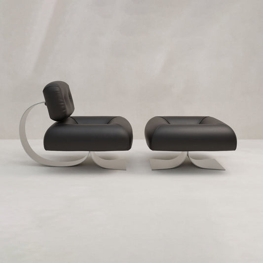 The Paolo Chair With Ottoman features modern black leather upholstery and a sleek bent metal base, paired with a matching ottoman. Set against a light gray background, it adds sophisticated style to any space.