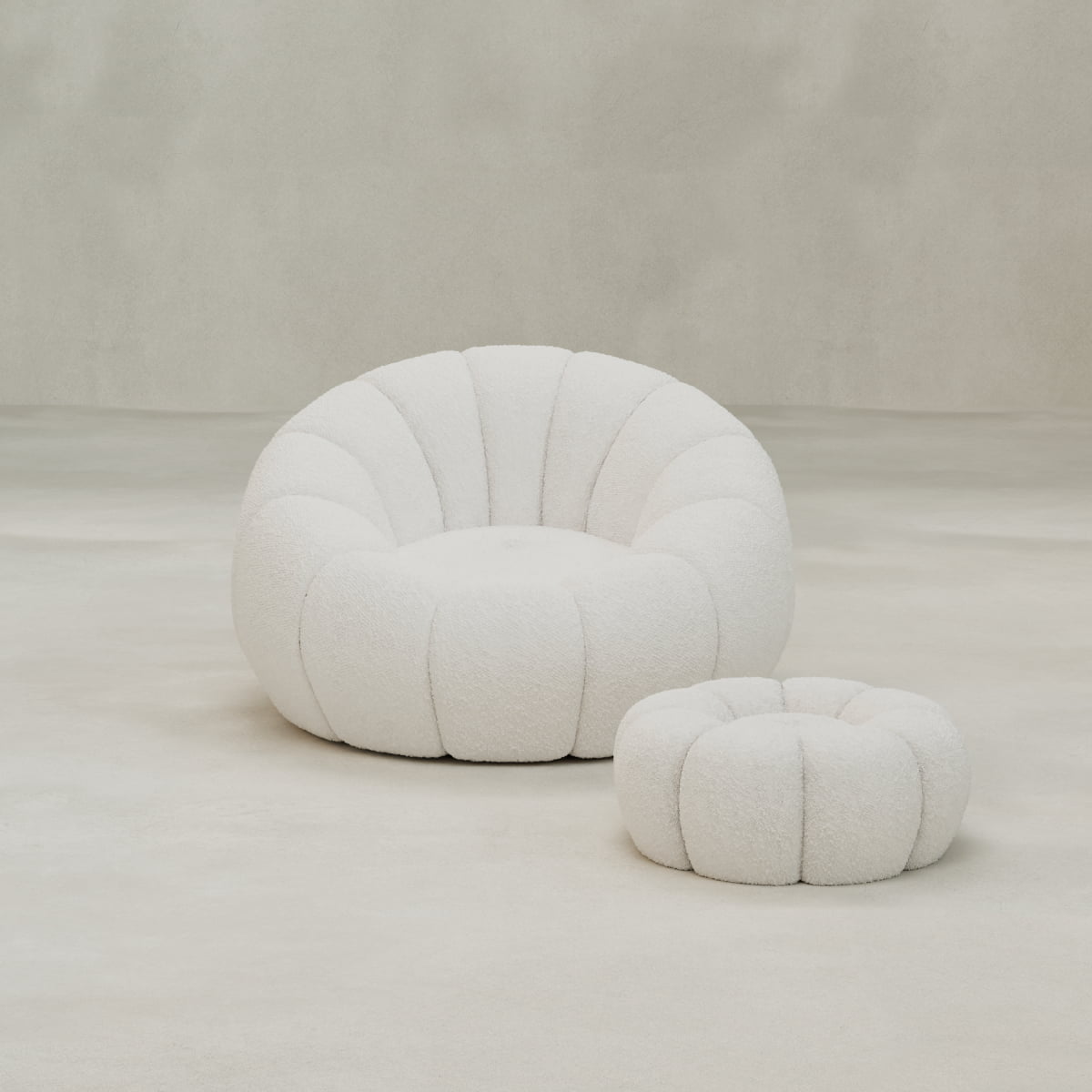 The Penelope Chair with Ottoman features plush, tufted bouclé upholstery in white. Set on a minimalist background, this cozy duo offers inviting comfort perfect for relaxation.