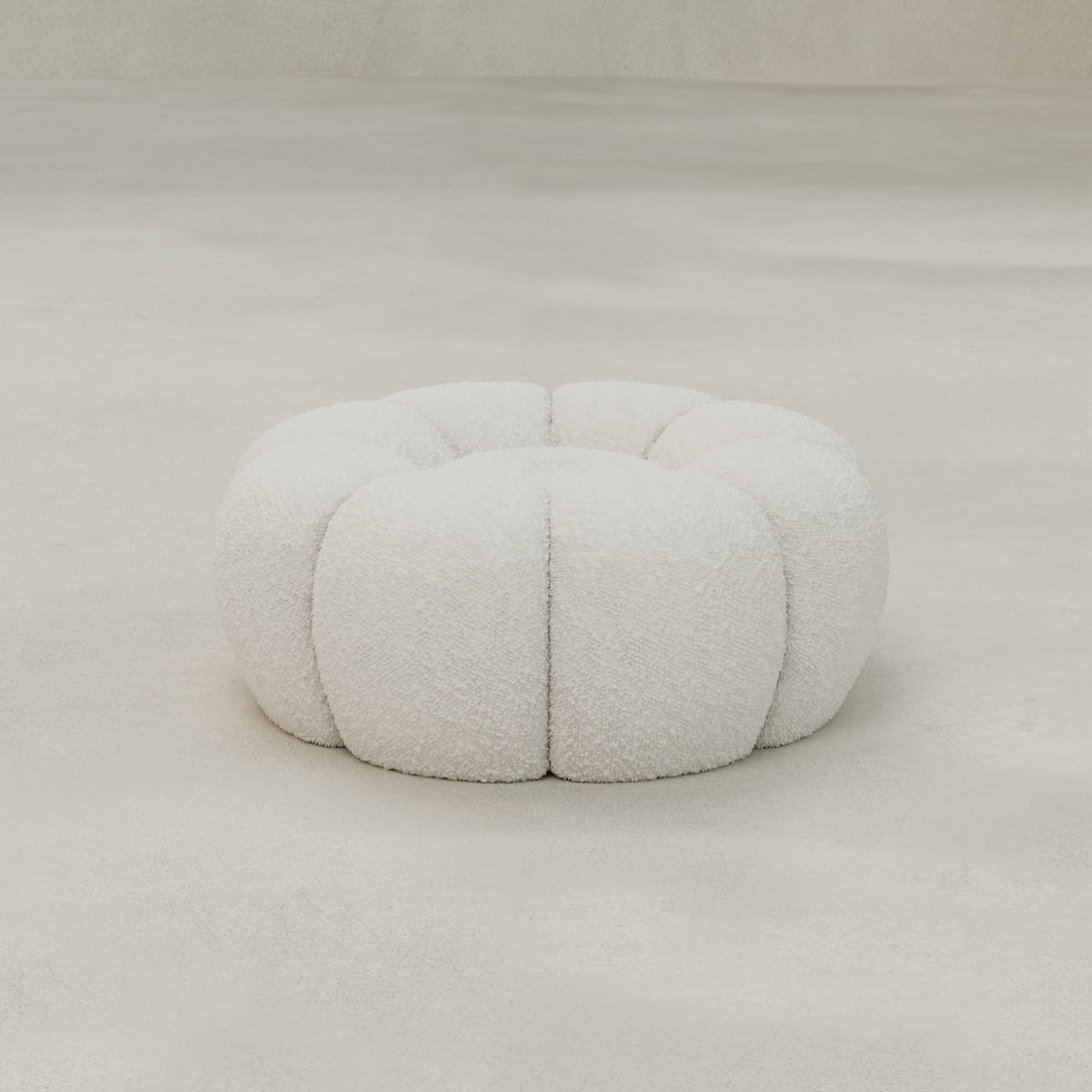 The Penelope Chair with Ottoman features a round, plush, white ottoman crafted from bouclé fabric with a tufted, textured surface, seen here on a smooth, light-colored floor in a minimalist setting.