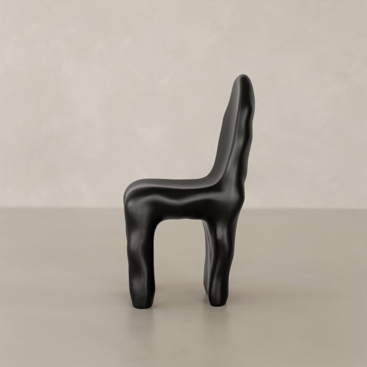 The Phantom Chair Rental features a black, sculptural design with smooth, organic curves and an abstract form, displayed on a neutral surface against a pale background that highlights modern craftsmanship.