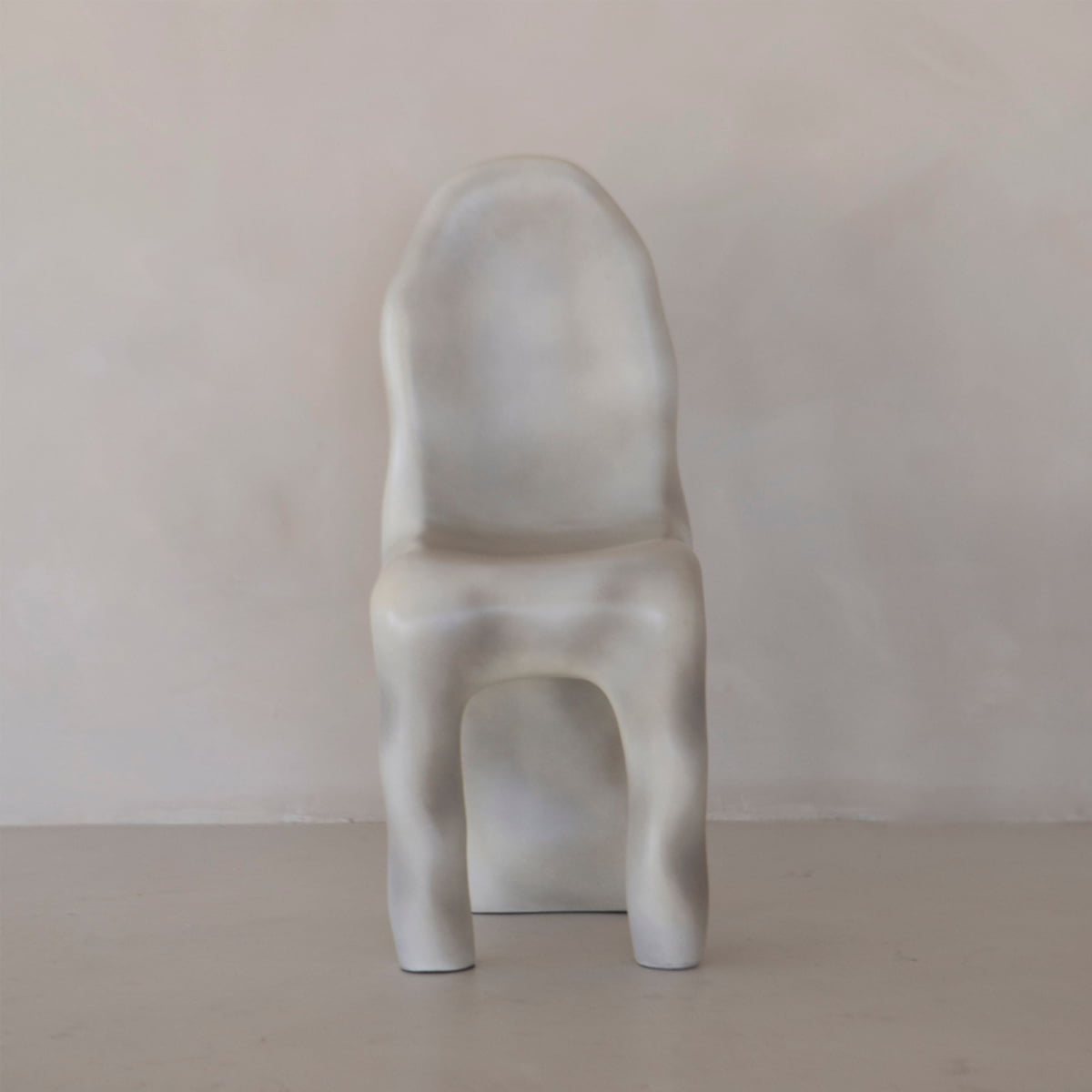 The Phantom Chair Rental features a sculptural, modern design with smooth, wavy lines and a matte light gray finish—an ideal showcase of contemporary craftsmanship against neutral walls and floors.