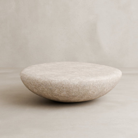 The Pluto Coffee Table features a smooth, round white design with a beige, textured surface, set against a matching minimalist background—an ideal chic centerpiece for modern interiors.