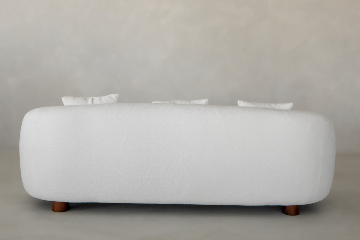 The Polar Bear Sofa features rounded edges, short wooden legs, and three white cushions for a luxurious touch. Shown from the back against a light gray background, its contemporary design stands out.