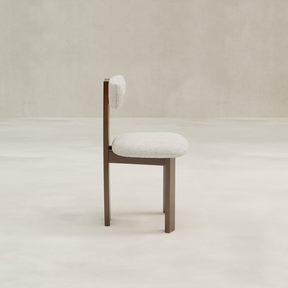 The Radley Dining Chair features a soft, rounded white bouclé seat and backrest with a minimalist wooden frame, shown in profile against a neutral light background.