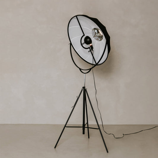 The Repertoire Standing Lamp features a sleek industrial tripod base and wide metal shade, adding contemporary elegance to any space with its visible bulb and trailing power cord.