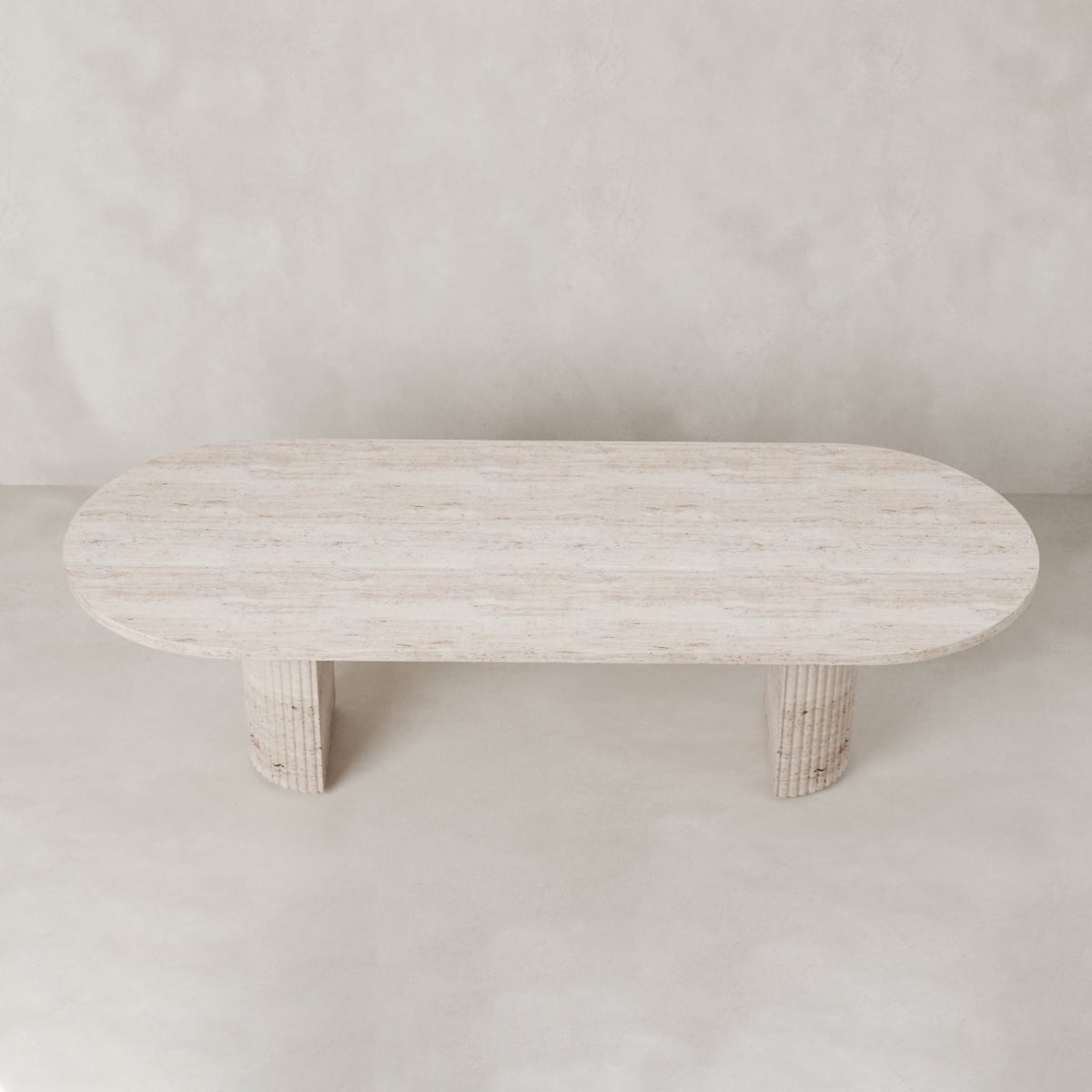 The Richmond Table features an oval, light natural stone top and two wide cylindrical legs, creating a sculptural statement piece against a neutral backdrop.