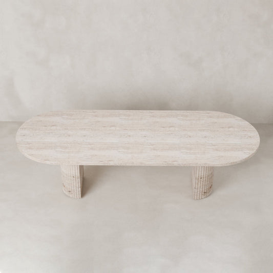 The Richmond Table features an oval, light natural stone top and two wide cylindrical legs, creating a sculptural statement piece against a neutral backdrop.