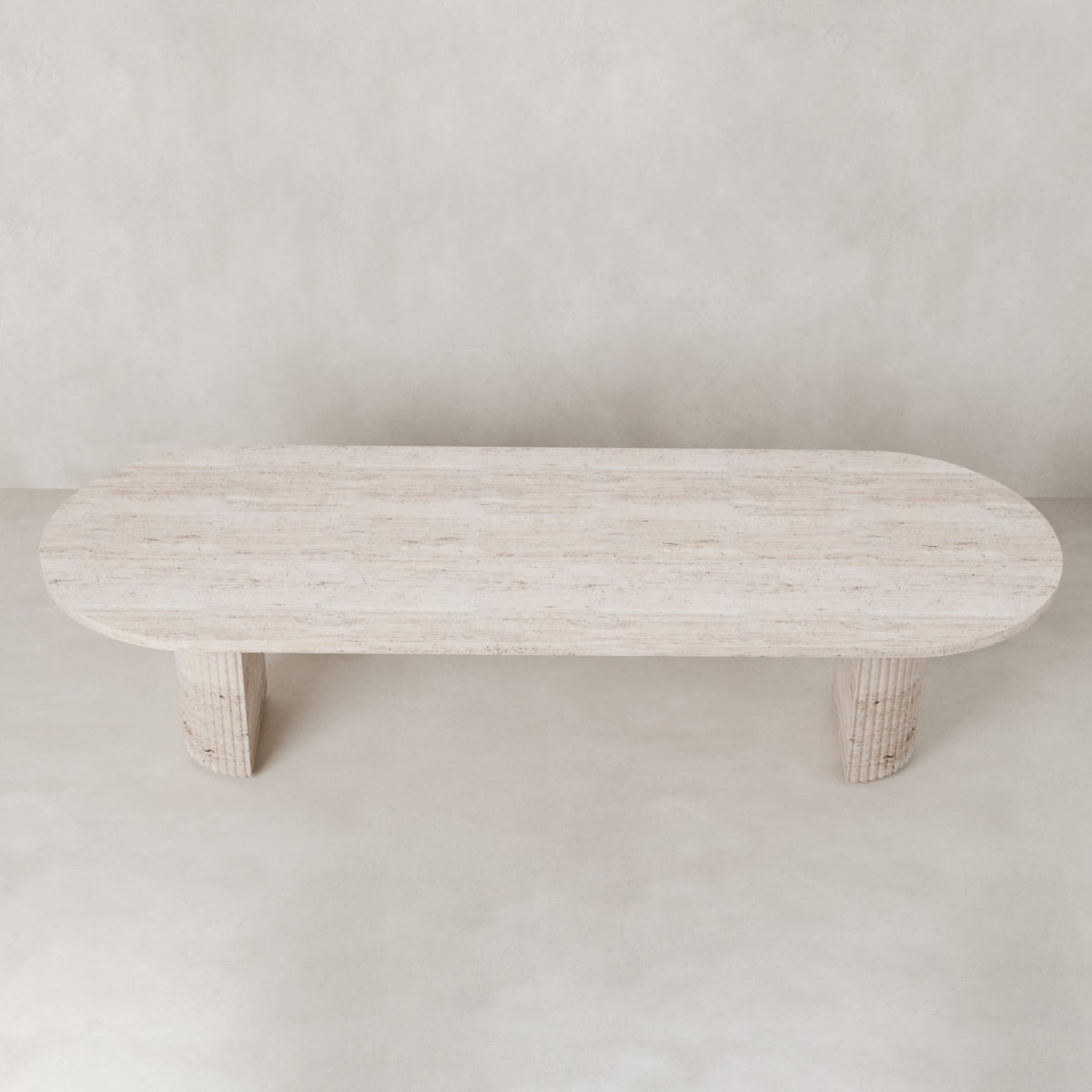 The Richmond Table is an oval, light natural stone coffee table with two cylindrical legs, set against a neutral background—ideal as a sculptural statement piece for any space.