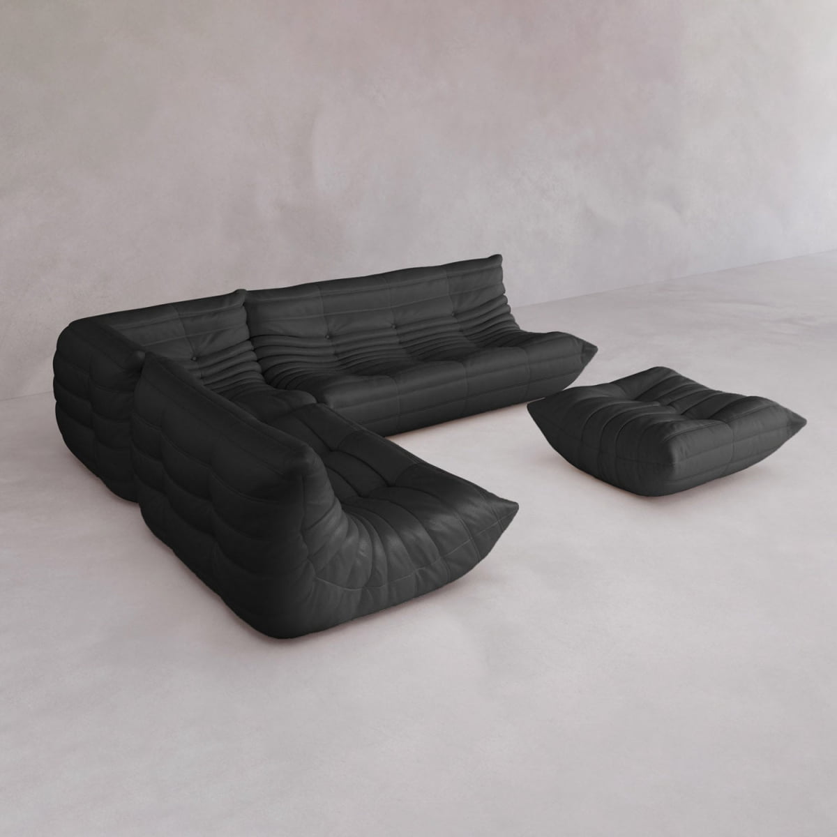 The Rolo Lounge Four Piece Sofa, a modern black sectional with tufted cushions and a matching ottoman, is arranged on a light floor against a pale minimalist wall.