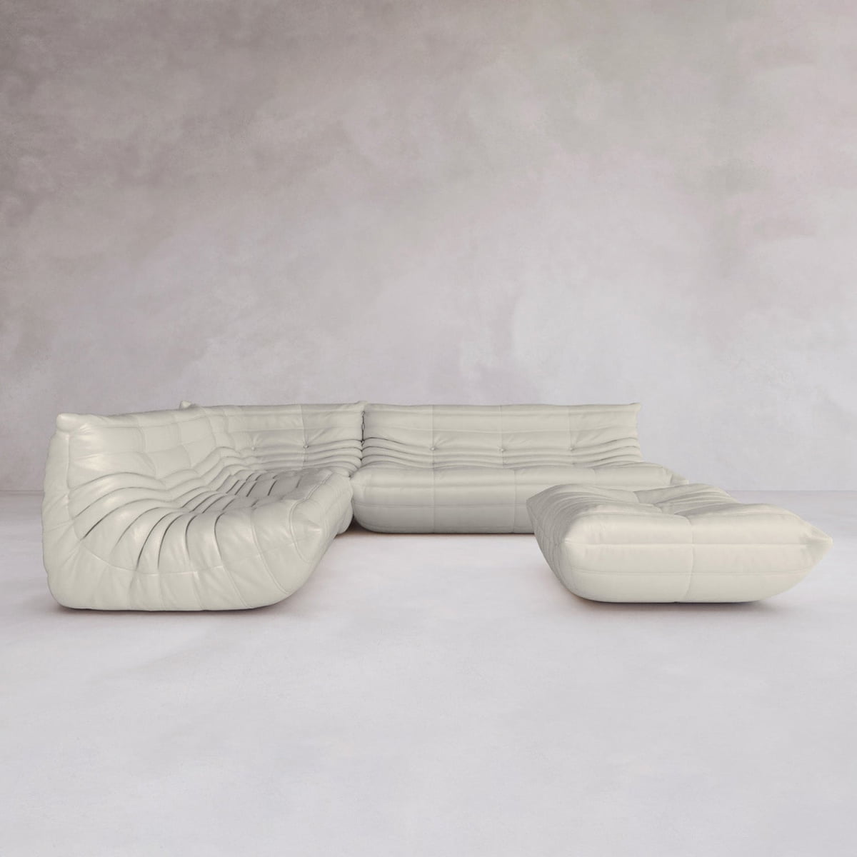 The Rolo Lounge Four Piece Sofa, a modern white modular sectional with deep tufting and mid-century design, forms an L-shape with wide, low seating and a plush look in a room with light gray walls and floors.