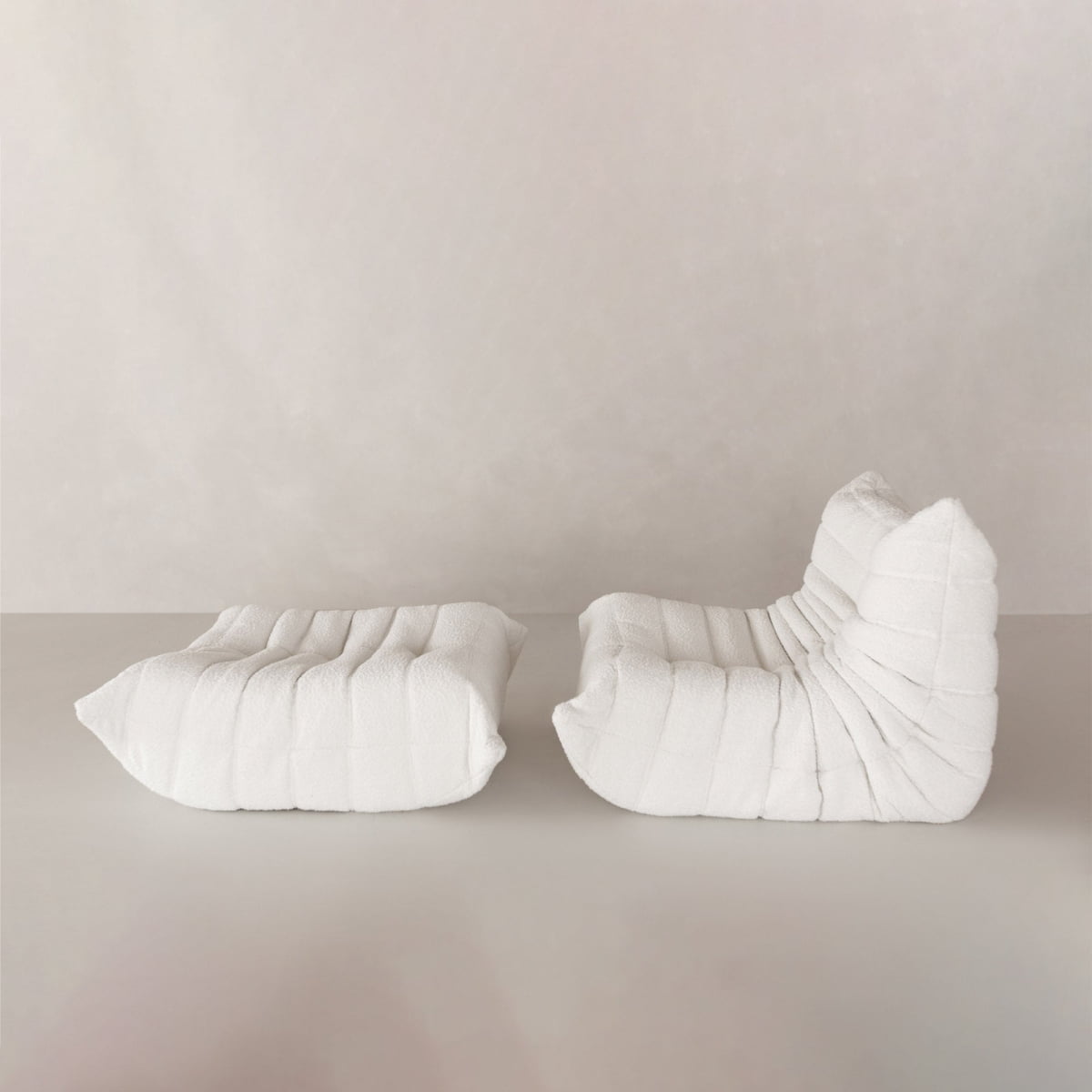 Two modern, minimalist Rolo Lounge Sofa Chairs with Ottoman, featuring a textured quilted surface and modular mid-century inspired design, are placed side by side against a light neutral background.