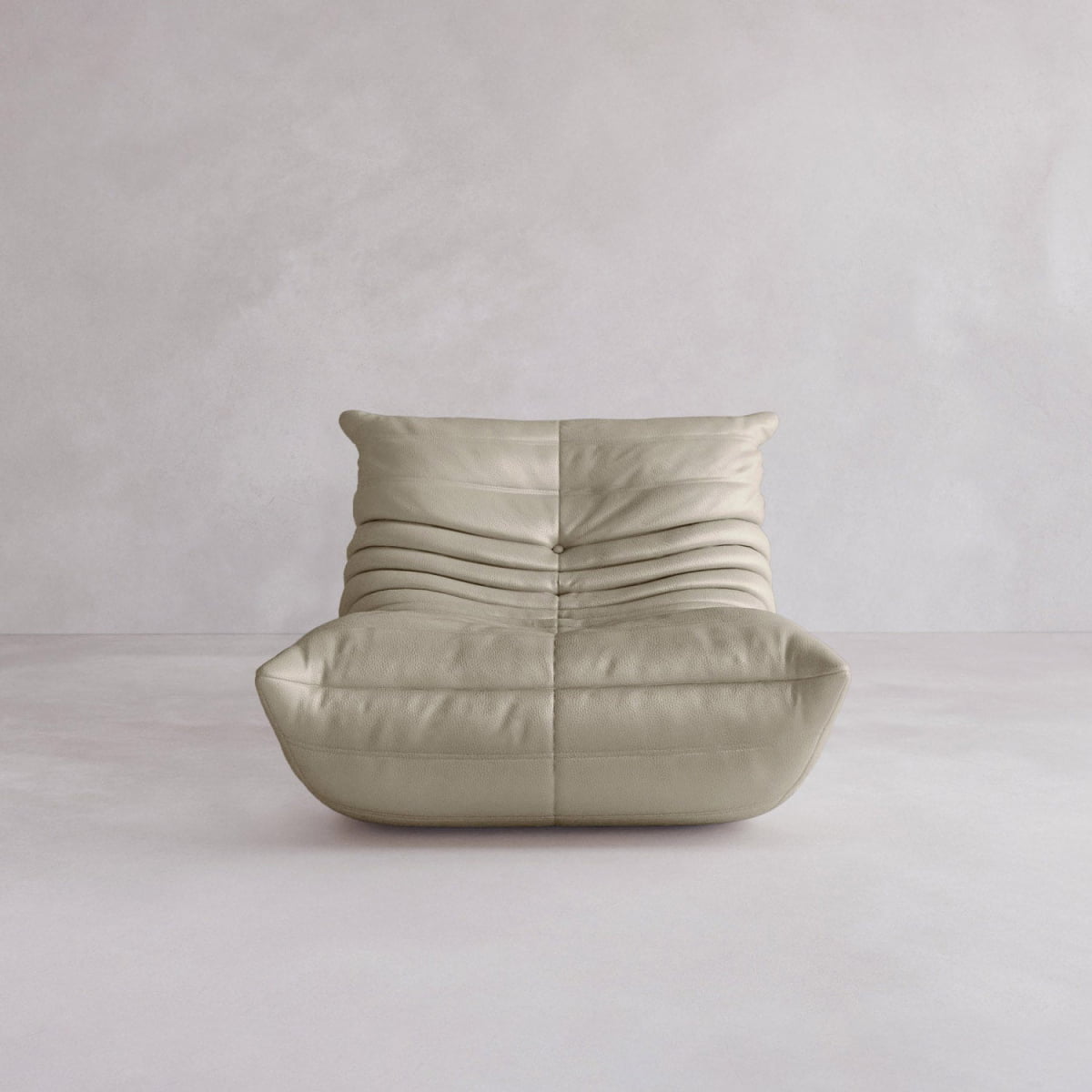 The Rolo Lounge Sofa Chair with Ottoman is a modern, armless beige leather chair with a low profile, deep seat, and pleated upholstery that evokes mid-century style, shown against a plain light gray background.
