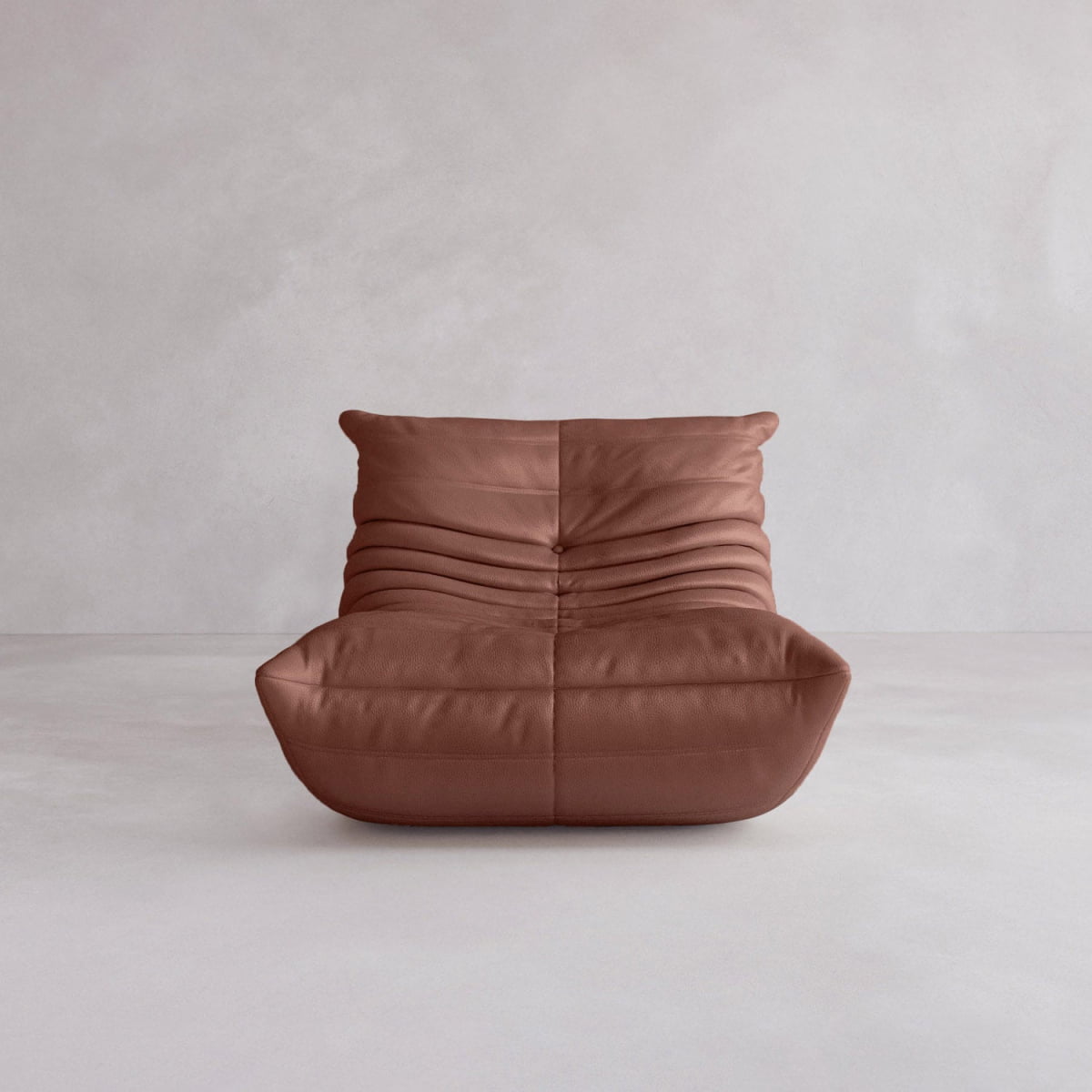 The Rolo Lounge Sofa Chair with Ottoman is a modern, armless lounge chair in soft brown leather with pleated details, inspired by mid-century design and featuring a deep seat—shown here against a light gray minimalist background.