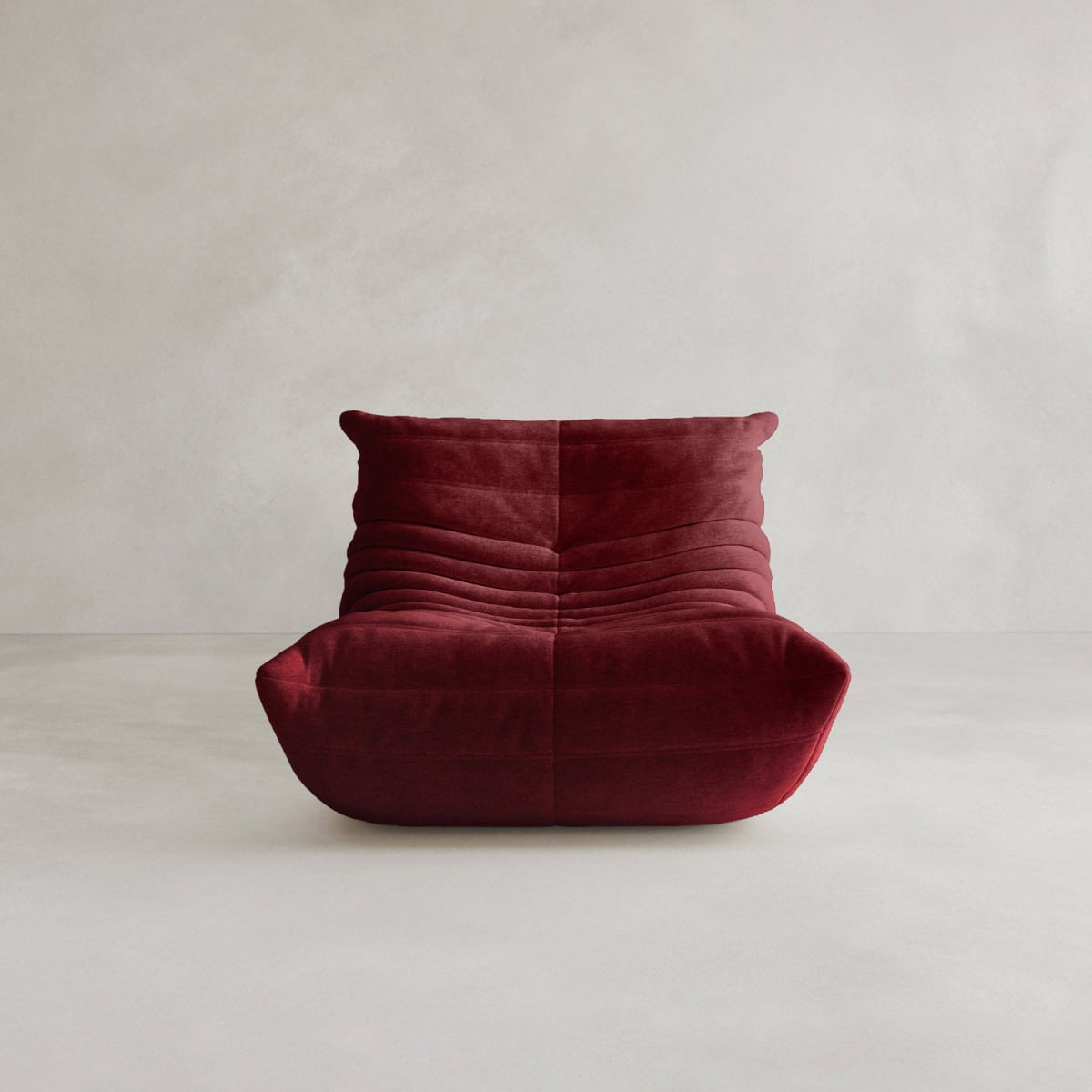 The Rolo Lounge Sofa Chair with Ottoman features deep red, velvet-like upholstery and horizontal tufted lines in a modern 70s-inspired design, shown against a plain light gray background.