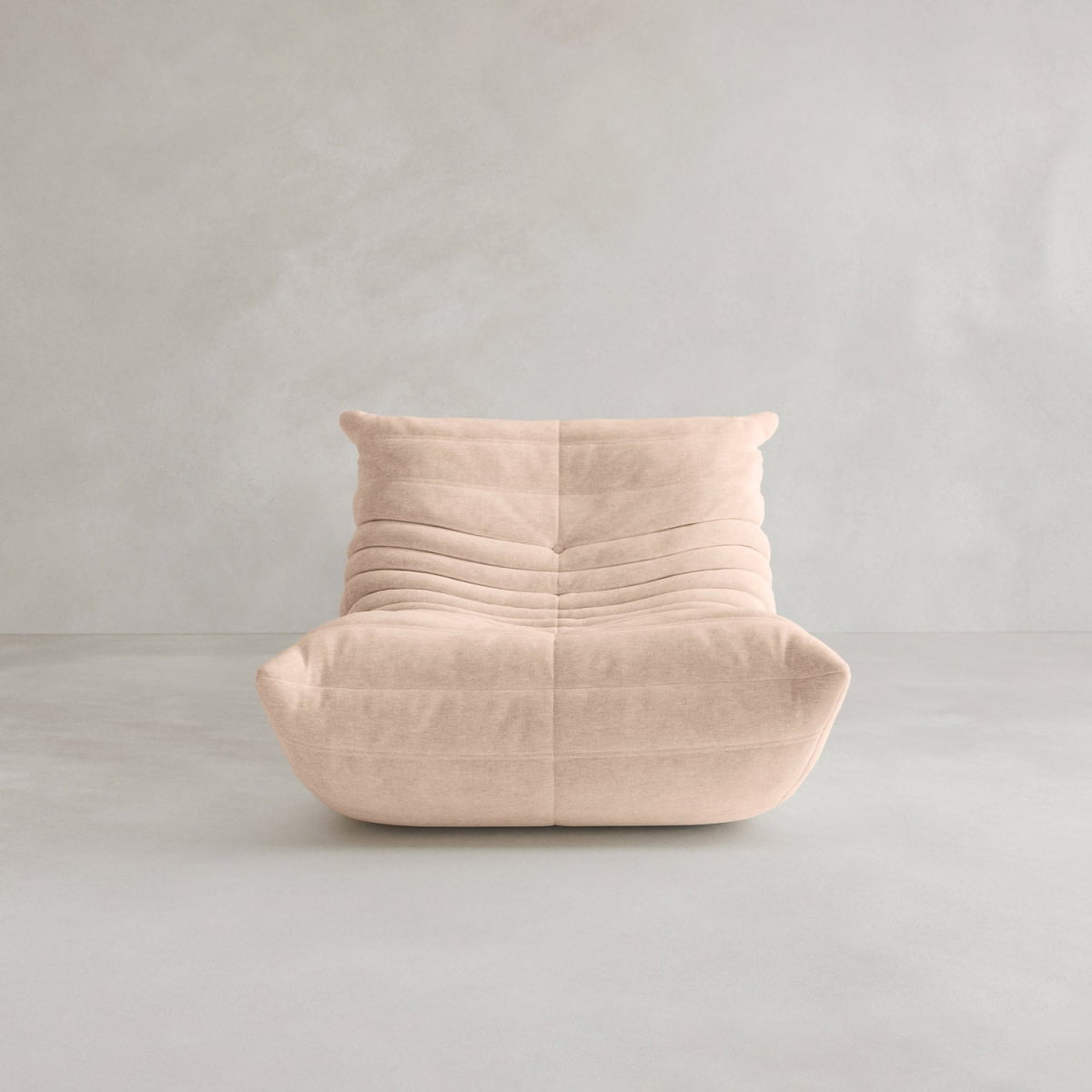 The Rolo Lounge Sofa Chair with Ottoman is a modern, armless beige chair featuring soft, plush fabric and horizontal tufting inspired by mid-century design, shown against a plain light gray wall and floor background.