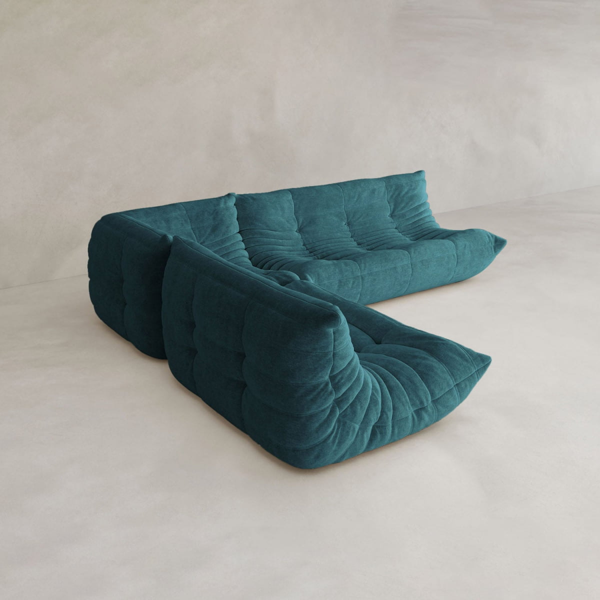 The Rolo Lounge Three Piece Sofa is a modern teal sectional with plush tufted cushions and a low, curved profile, perfect for contemporary spaces with minimalist floors and neutral, textured walls.