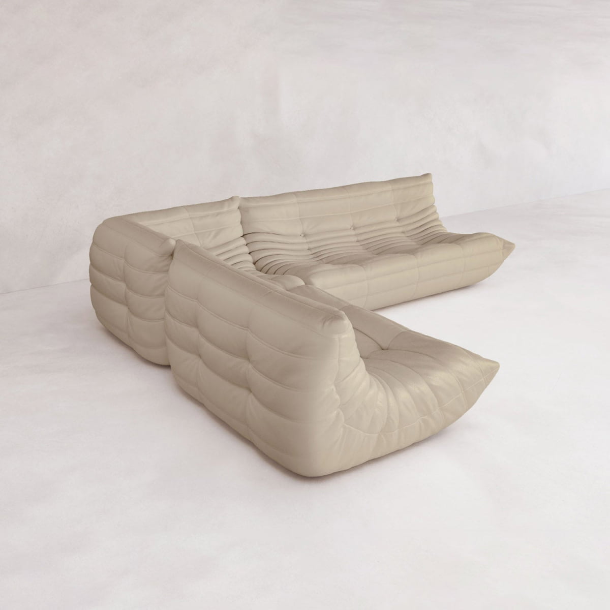 The Rolo Lounge Three Piece Sofa, a cream-colored modular sectional with tufted, plush cushions and a low profile inspired by mid-century design, sits on a light floor in a bright, minimal room.