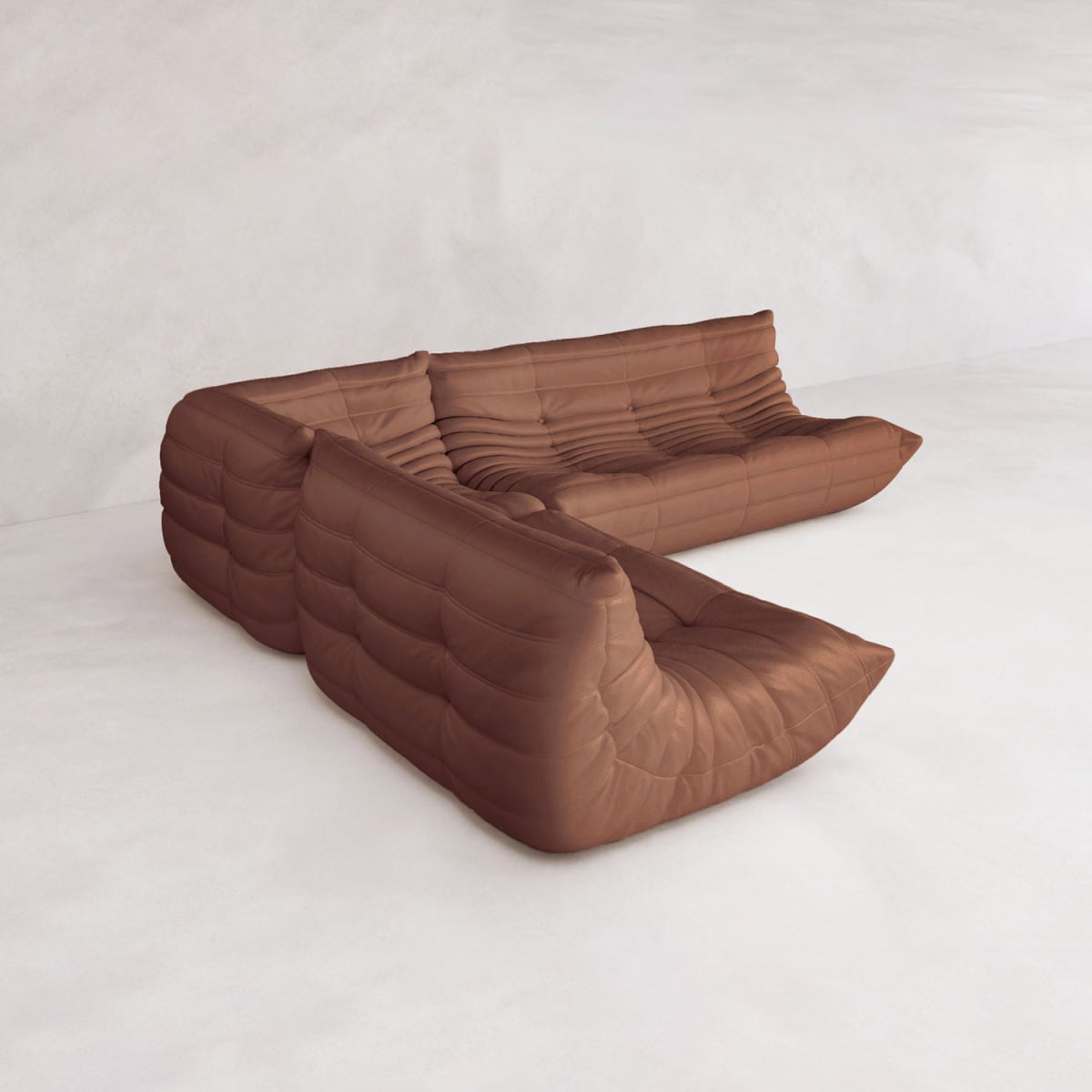The Rolo Lounge Three Piece Sofa, a modular brown sectional with tufted, low-profile design, evokes mid-century style as it sits on a light floor against a white wall.