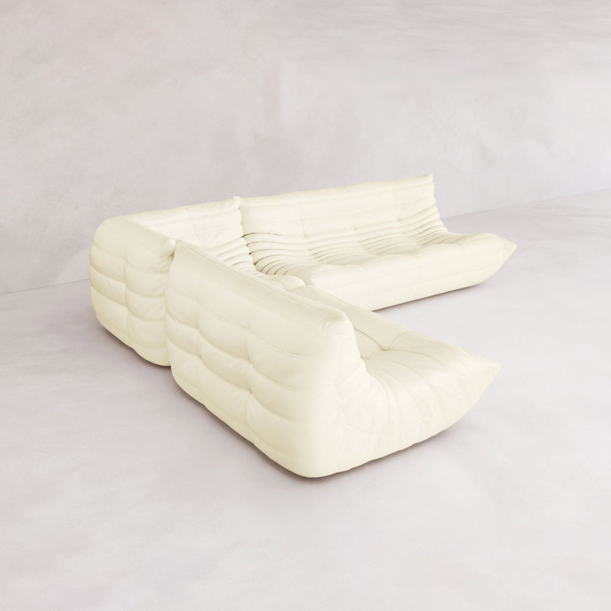 The Rolo Lounge Three Piece Sofa, a modern white modular sectional with plush tufted upholstery and low profile, brings mid-century flair and versatile design to a minimalist, light-toned room.