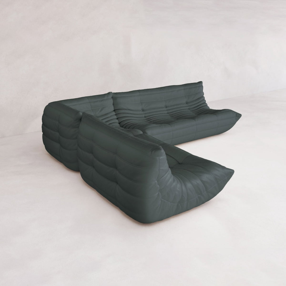 The Rolo Lounge Three Piece Sofa, a modern modular sectional in dark green with tufted cushions and a low profile inspired by mid-century design, sits on a light floor against a plain, textured white wall.