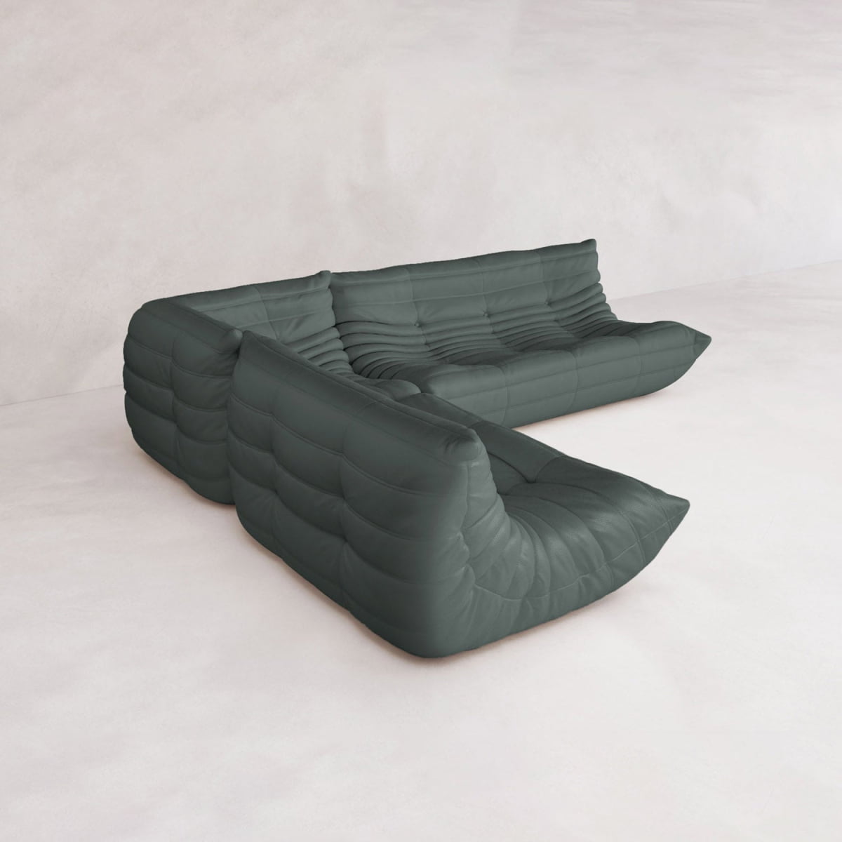 The Rolo Lounge Three Piece Sofa is a modern, dark green modular sofa with low, armless seats and tufted, pillow-like cushions in an L-shape, inspired by mid-century modular systems, set against a light minimalist background.