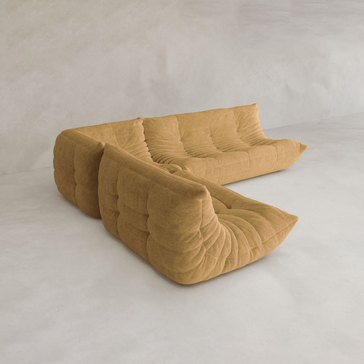The Rolo Lounge Three Piece Sofa, in mustard yellow with tufted cushions and a low, modern design, forms a modular sectional set on a light neutral floor against a plain textured wall.