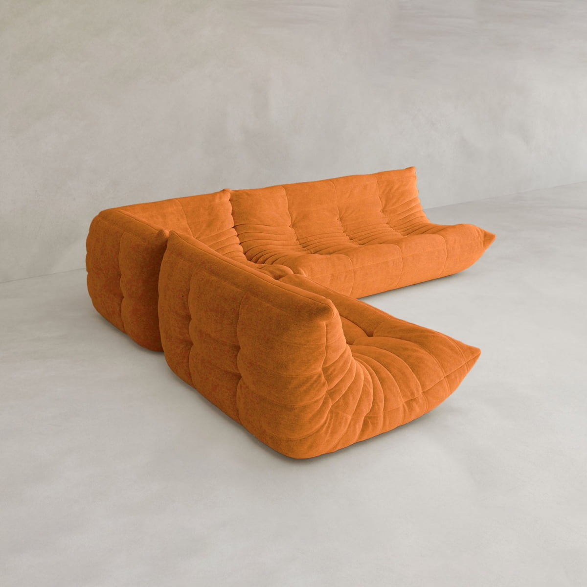 The Rolo Lounge Three Piece Sofa, a modern mid-century-inspired orange tufted sectional with plush cushions and a low profile, sits on a light gray floor against a matching wall—ideal for contemporary spaces.