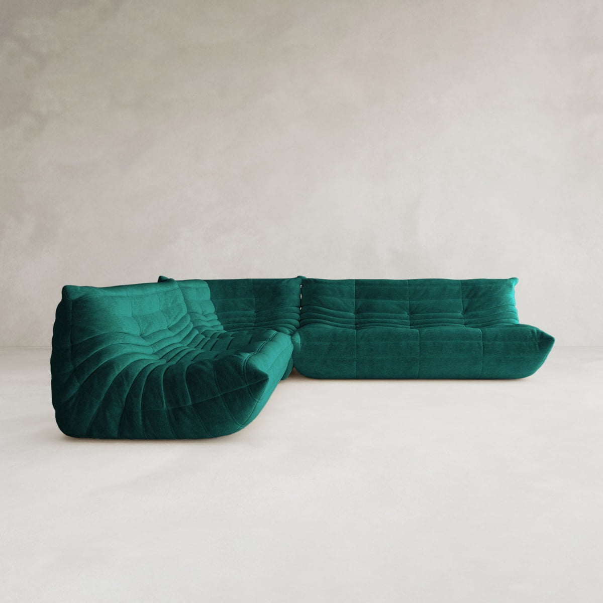 The Rolo Lounge Three Piece Sofa in emerald green velvet with a mid-century tufted design sits on a minimalist light floor against a plain, textured off-white wall.