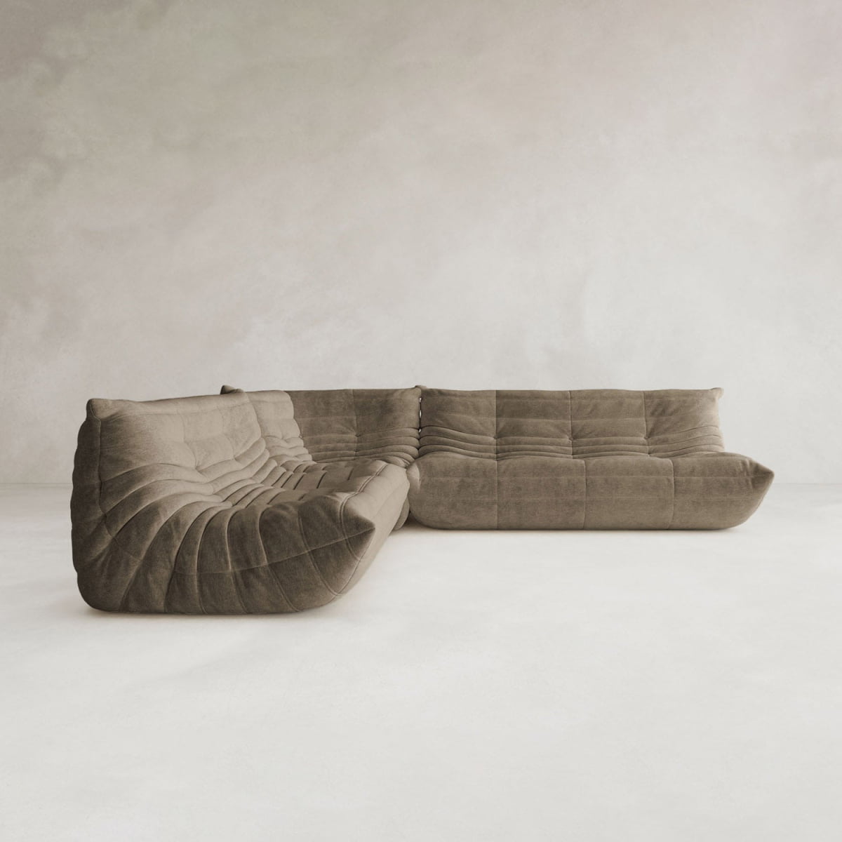 The Rolo Lounge Three Piece Sofa, featuring soft brown textured upholstery and deep plush cushions, sits on a light floor against a minimalist grey wall.