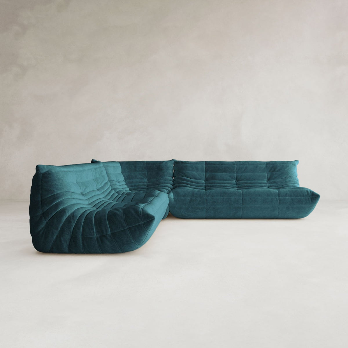The Rolo Lounge Three Piece Sofa, with its modern teal upholstery and low-profile tufted design, brings contemporary style to a minimalist room featuring light walls and flooring.