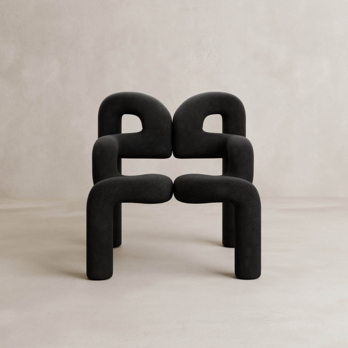Two modern black Spider Chair Rentals with neotenic geometry are stacked before a neutral beige wall, forming a geometric, symmetrical composition and providing a unique seating experience.