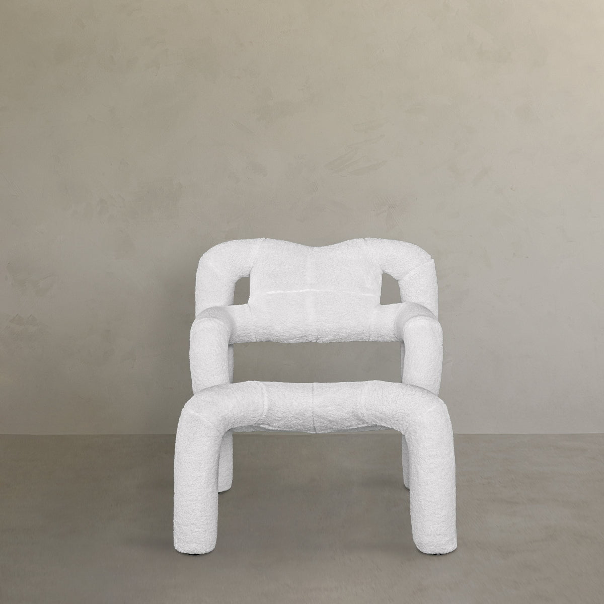 The Spider Chair Boucle features neotenic geometry, curved legs and armrests, and white textured upholstery, creating a unique seating experience against a neutral beige wall and smooth gray floor.