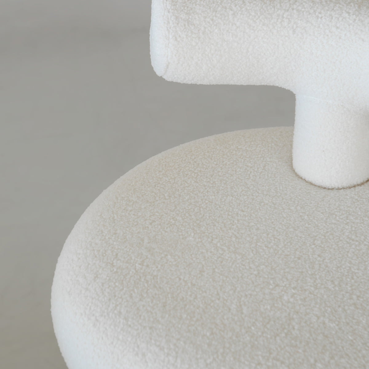 Close-up of the Teddy Chair Rental, upholstered in off-white boucle fabric. Its rounded seat and curved backrest create a minimal, luxurious statement piece against a neutral background.