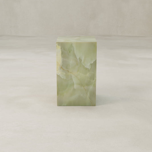The Verdaine Onyx Plinth - Tall, crafted from light green onyx with natural veining, adds a sculptural touch and enhances contemporary spaces when placed on a smooth, light-colored surface against a neutral background.