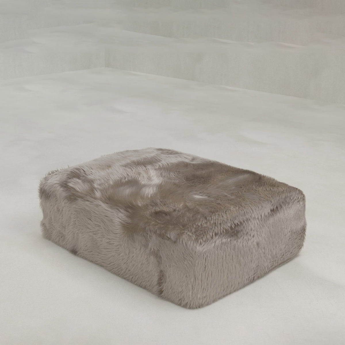 The Yeti Ottoman, featuring a rectangular shape and plush faux fur upholstery, is displayed on a light floor in a minimalist room with neutral tones.
