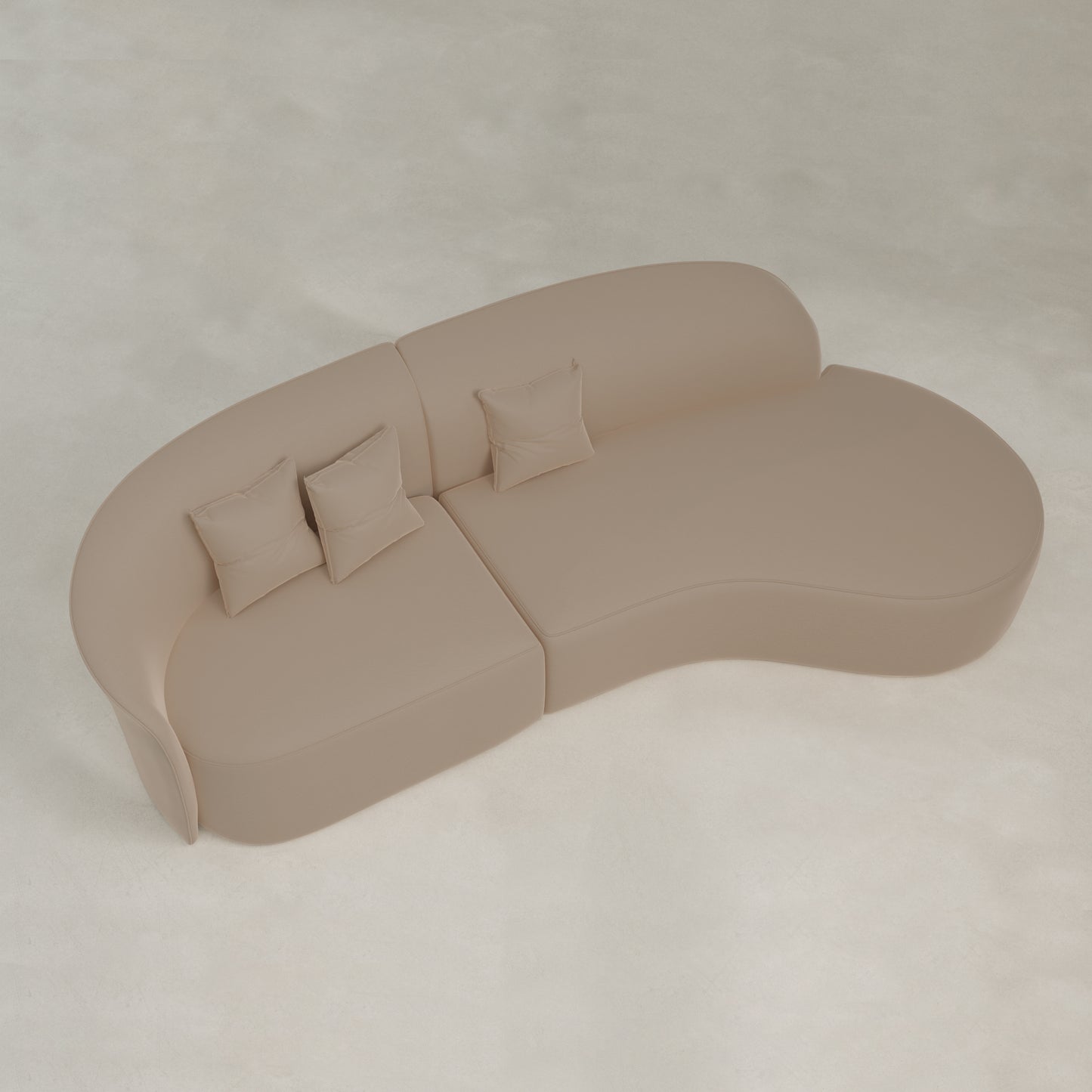 The Marlow Curved Modular Three Seater Sofa features beige velvet upholstery and includes three matching square pillows, shown from above on a light-colored floor.