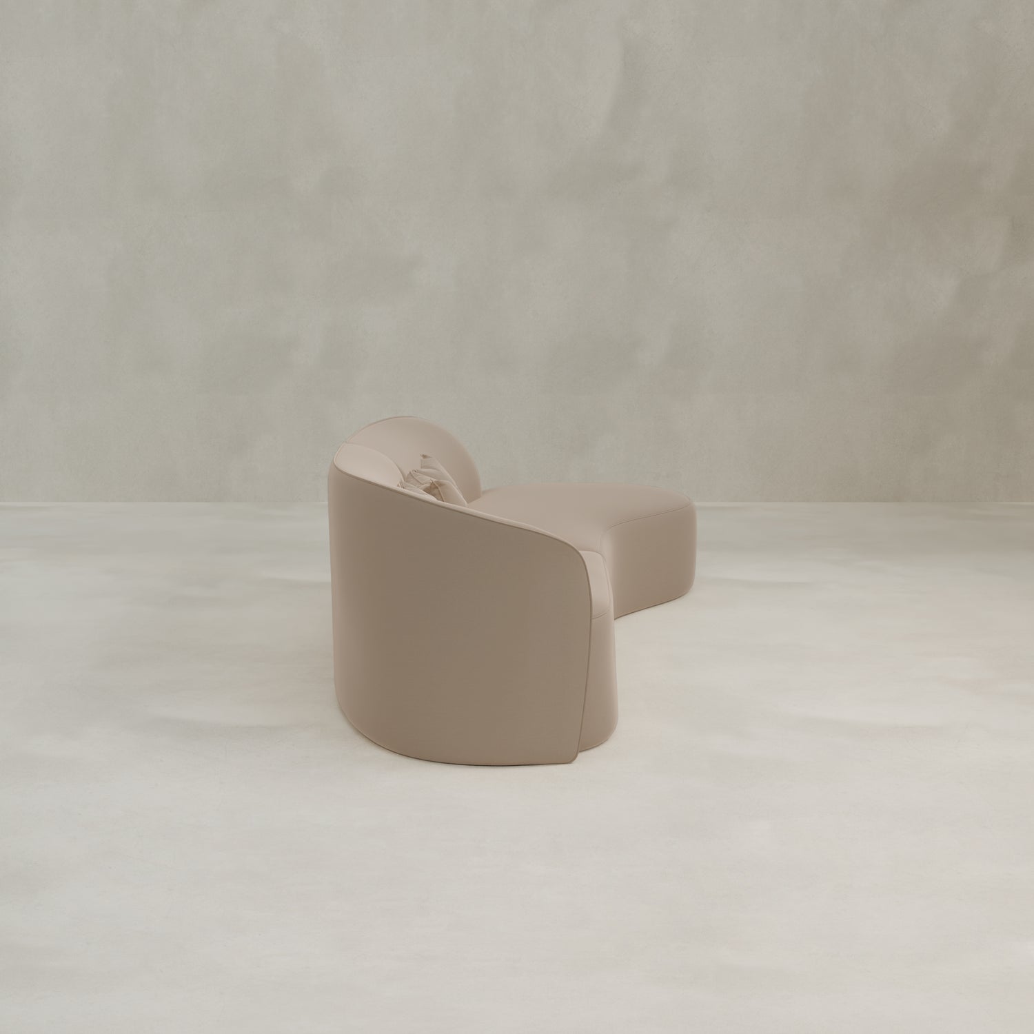 The Marlow Curved Modular Three Seater Sofa, in light beige with a modern design and smooth finish, sits on a neutral floor against a textured light gray wall.