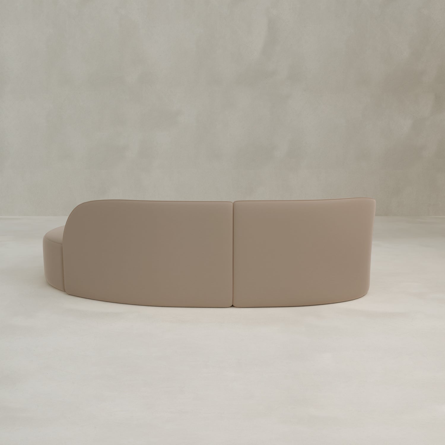 The Marlow Curved Modular Three Seater Sofa with a modern aesthetic sits on a light floor against a neutral textured wall, viewed from the back.