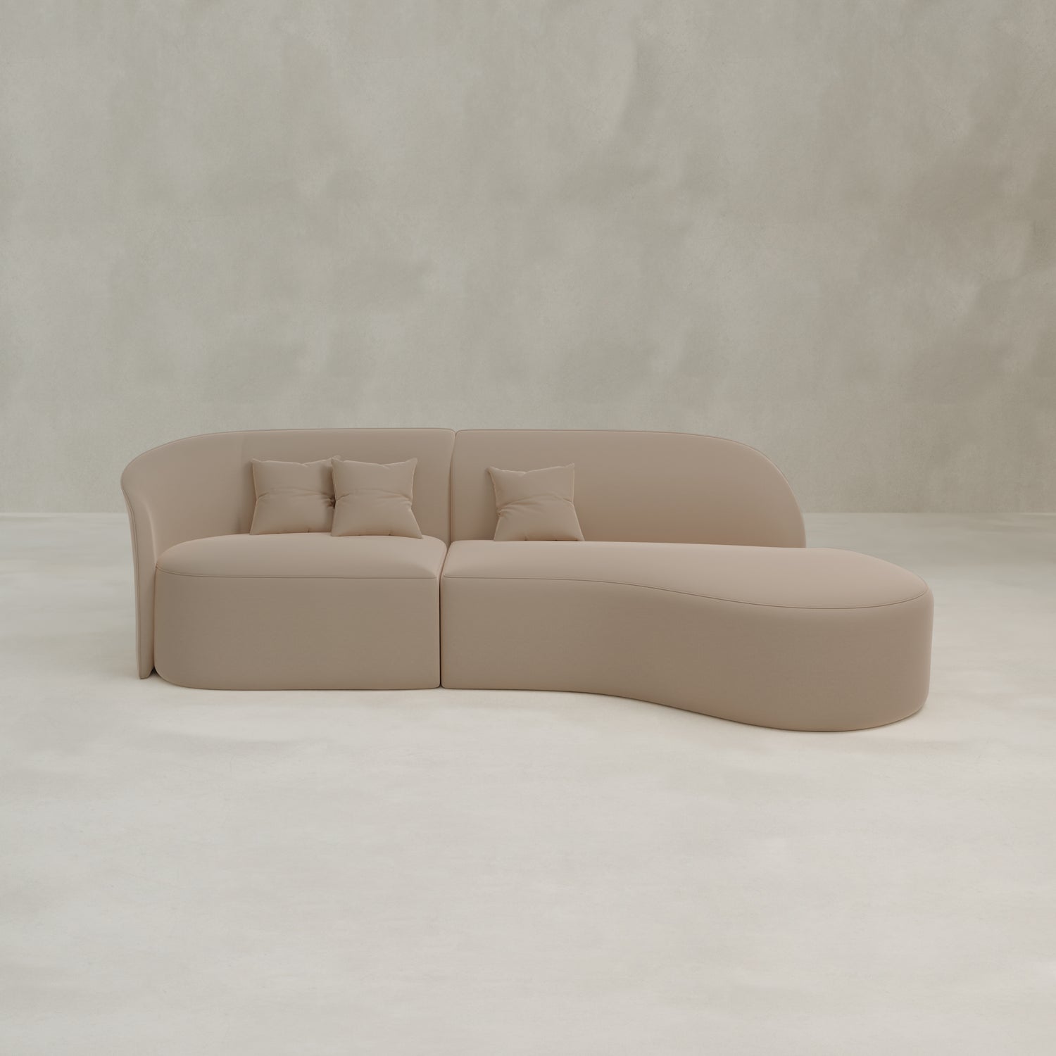 The Marlow Curved Modular Three Seater Sofa features a modern, minimalist beige design with a right-side curved chaise lounge, three matching square pillows, and luxurious upholstery.
