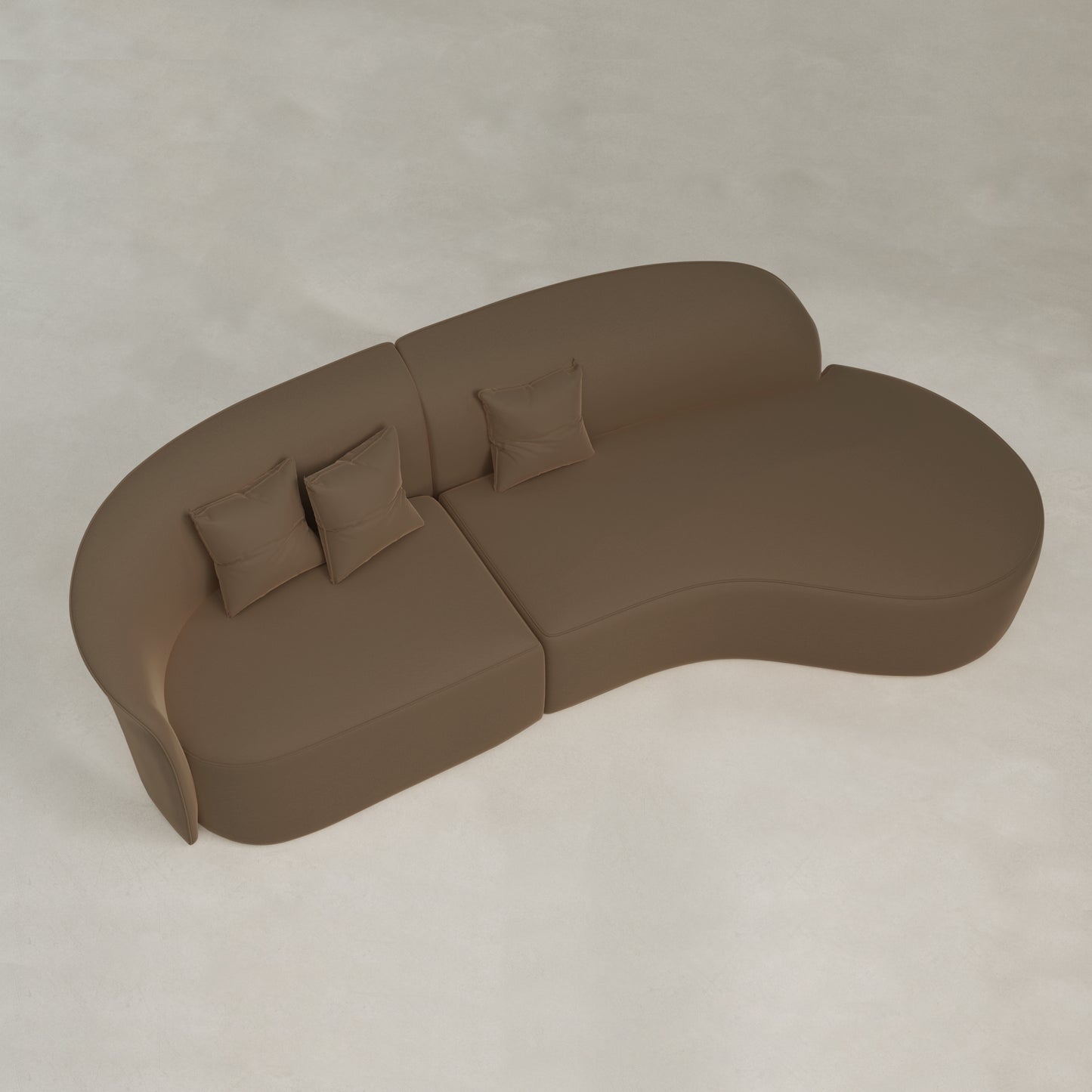 The Marlow Curved Modular Three Seater Sofa, with a modern kidney shape and three matching square pillows, sits on a light floor, viewed from above, highlighting its sleek contemporary design.