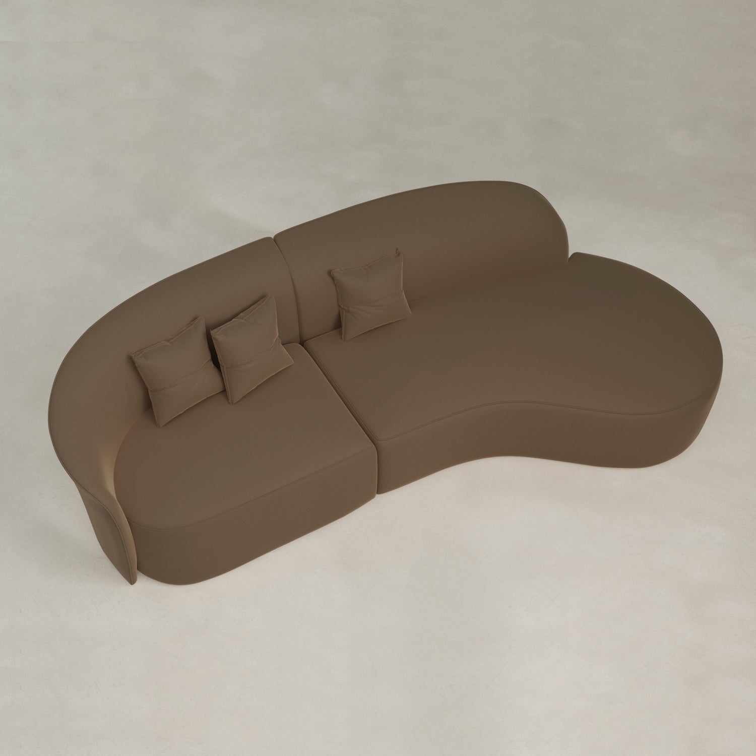 The Marlow Curved Modular Three Seater Sofa, with a modern kidney shape and three matching square pillows, sits on a light floor, viewed from above, highlighting its sleek contemporary design.