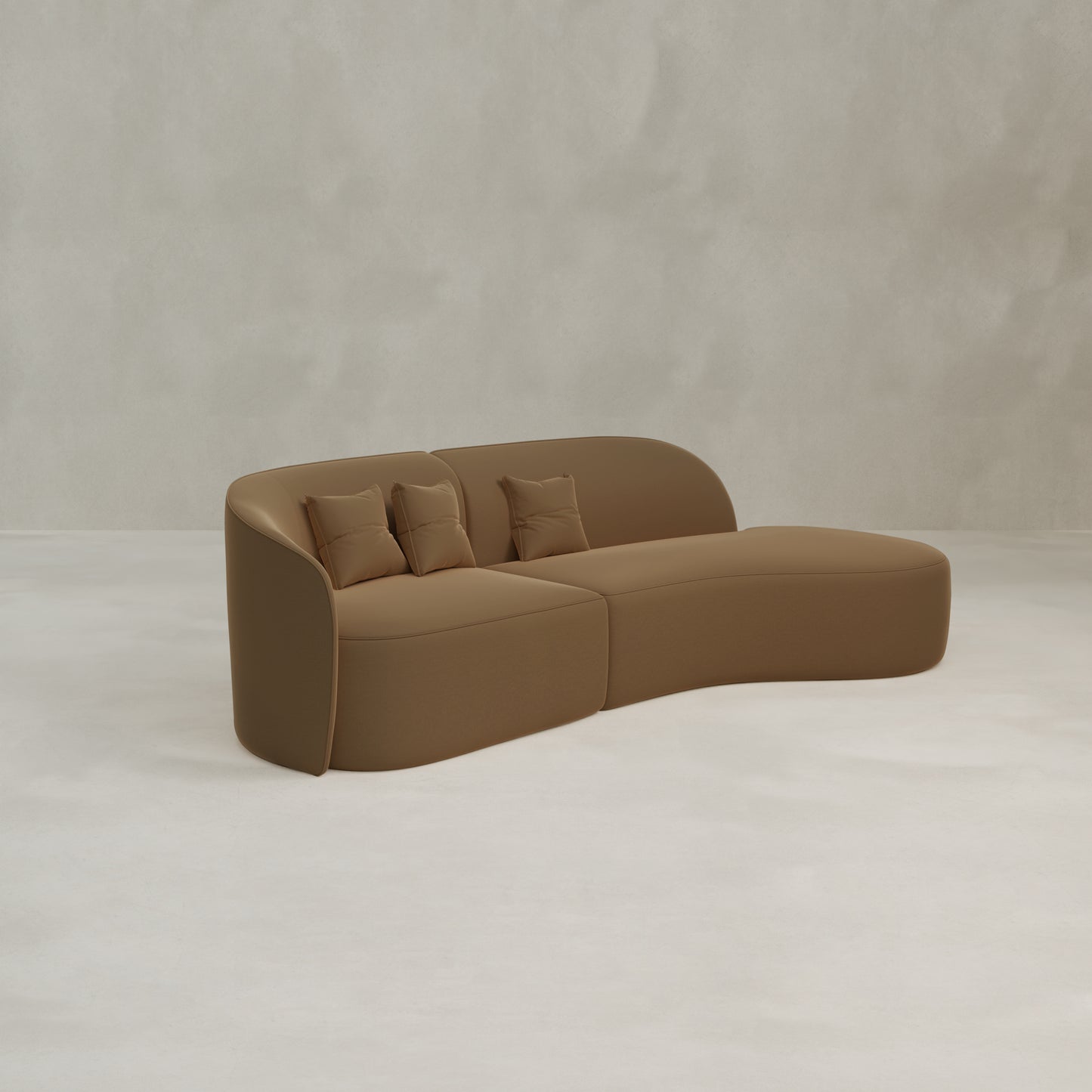 The Marlow Curved Modular Three Seater Sofa, featuring a modern velvet design and three matching cushions, is placed on a light floor against a textured beige wall.