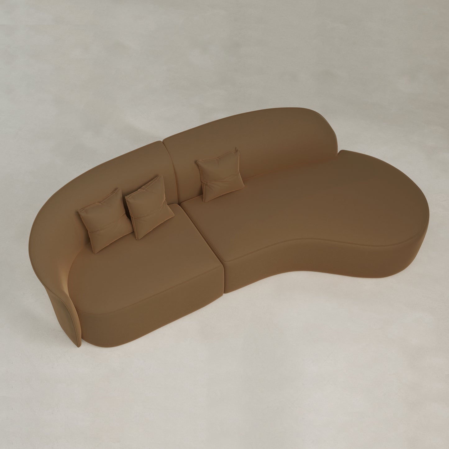 The Marlow Curved Modular Three Seater Sofa features luxurious brown velvet upholstery and includes three matching square pillows, elegantly placed on a light-colored textured floor.