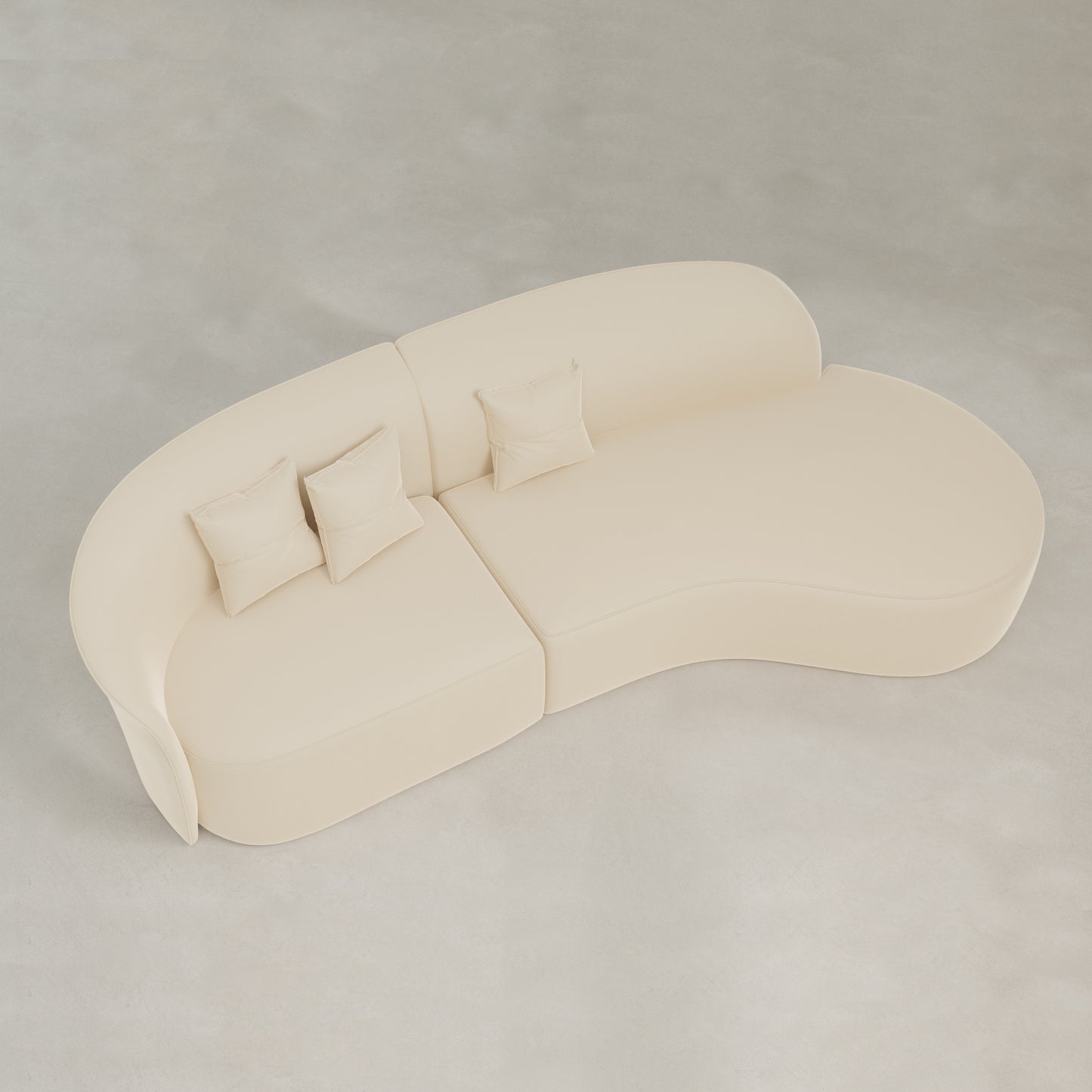 The Marlow Curved Modular Three Seater Sofa features modern cream-colored velvet upholstery and comes with three matching square pillows, shown from above on a light floor.