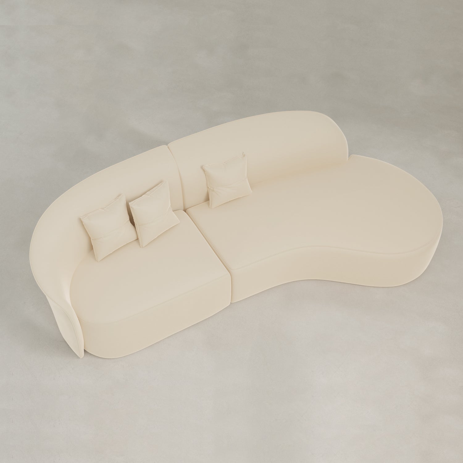 The Marlow Curved Modular Three Seater Sofa features modern cream-colored velvet upholstery and comes with three matching square pillows, shown from above on a light floor.